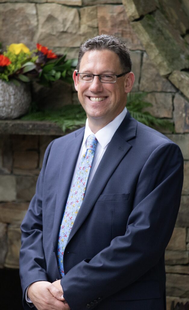 A man in a suit and tie standing next to a wall.